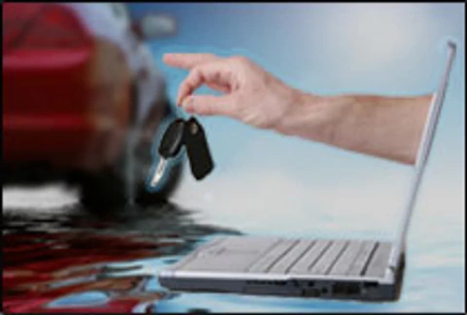 Hand delivering car keys from a laptop with a vehicle in the background